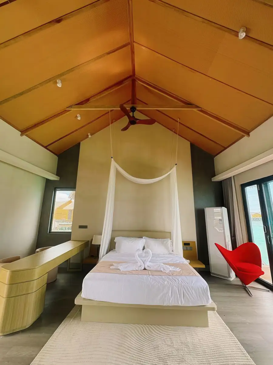 An elegant bedroom at Cupid Resort near Semporna with a canopy bed facing the sea, modern furniture, authentic wooden floors with glossy hardwood floors, and air conditioning.