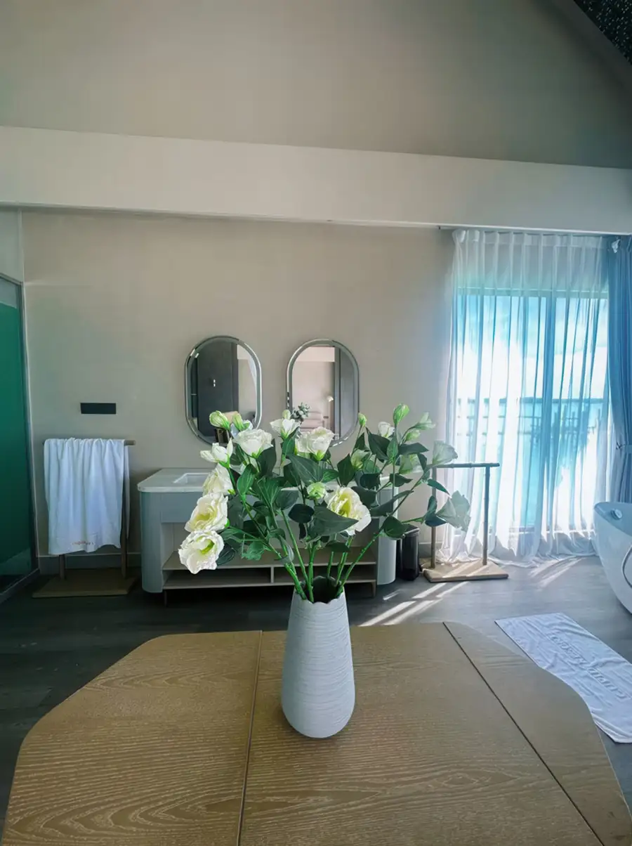 A modern bedroom at Cupid Resort in Semporna showcasing a designer vanity with floral accents, warm wooden plank floor with varnished timber flooring, and AC.