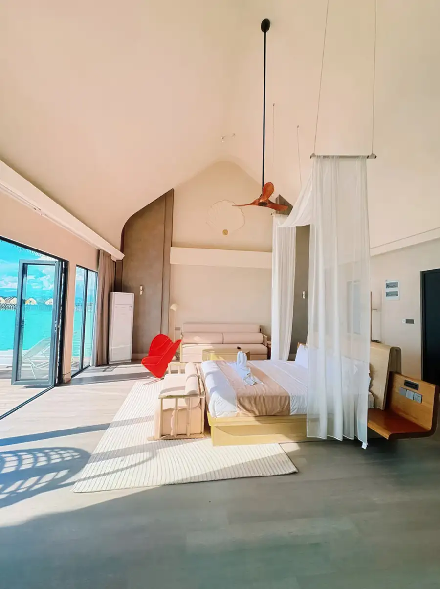 An expansive bedroom at Cupid Resort near Pulau Bum Bum with a large bed facing panoramic glass doors opening onto the private balcony with seaviews, smooth wooden boards, and air con.