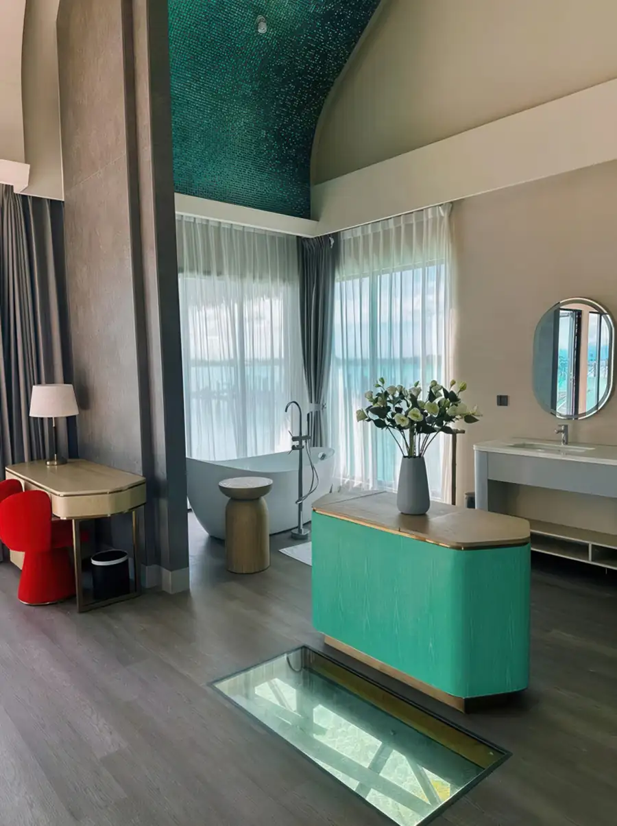 A luxury room at Cupid Resort on the Celebes Sea featuring a soaking tub by the window, glass floor panels, polished teak wood floors, and AC.